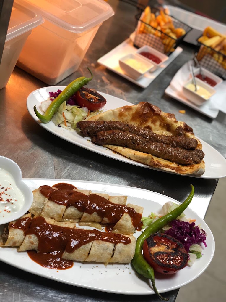 Adana kebab op pide en beyti met tomatensaus, friet en salade bij Kismet Lokanta